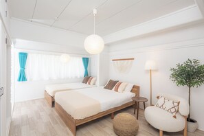 A modern bedroom with two beds, a round ottoman, a floor lamp, and a potted plant. - Villa CANGGU Osaka/Baika Modern Bali (Konohana-ku, Osaka)