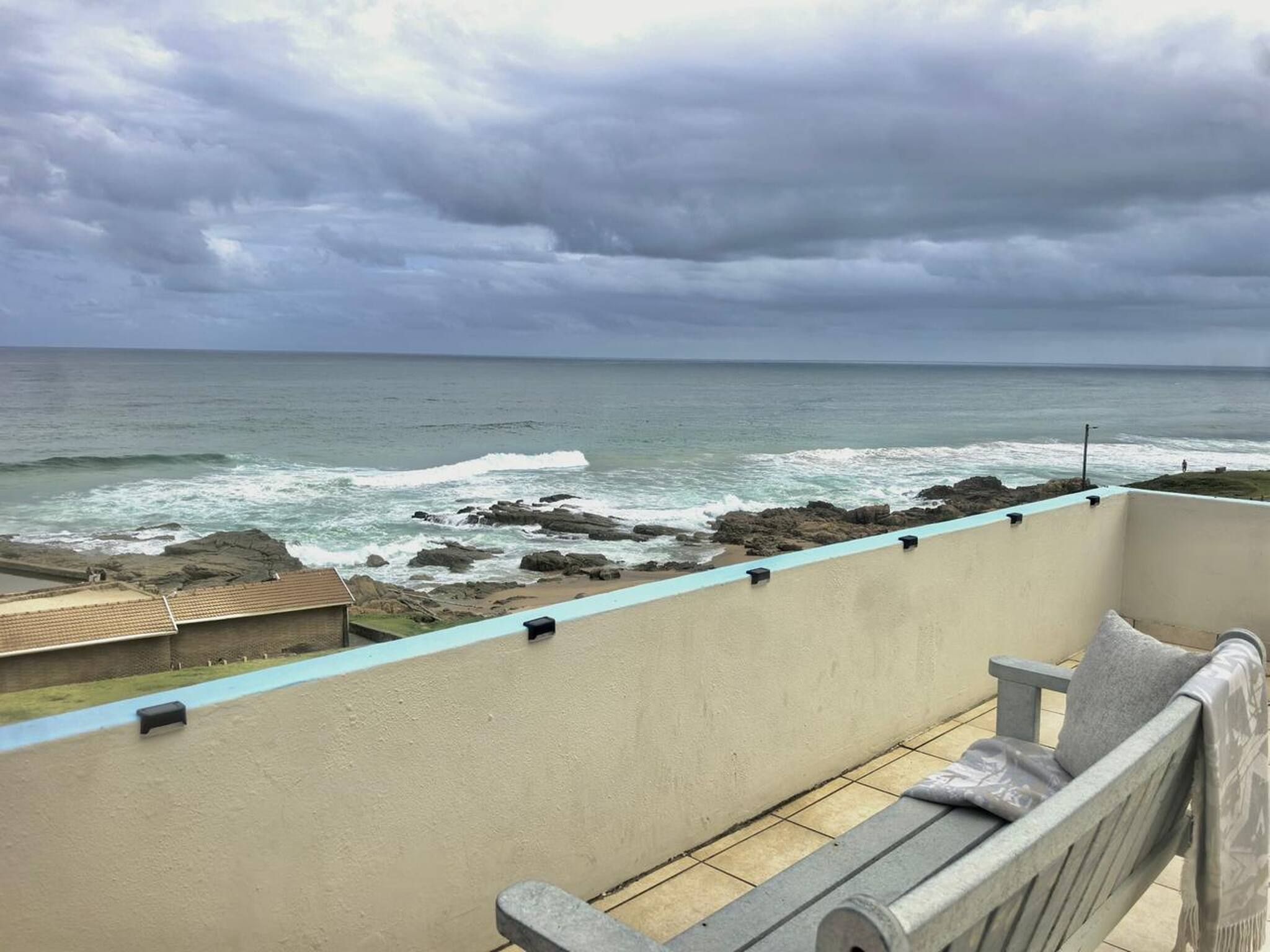 A balcony with a view of the ocean and rocky shoreline.