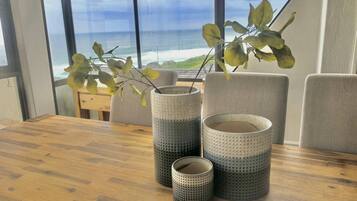 A wooden table with three perforated vases and a plant with yellow leaves.