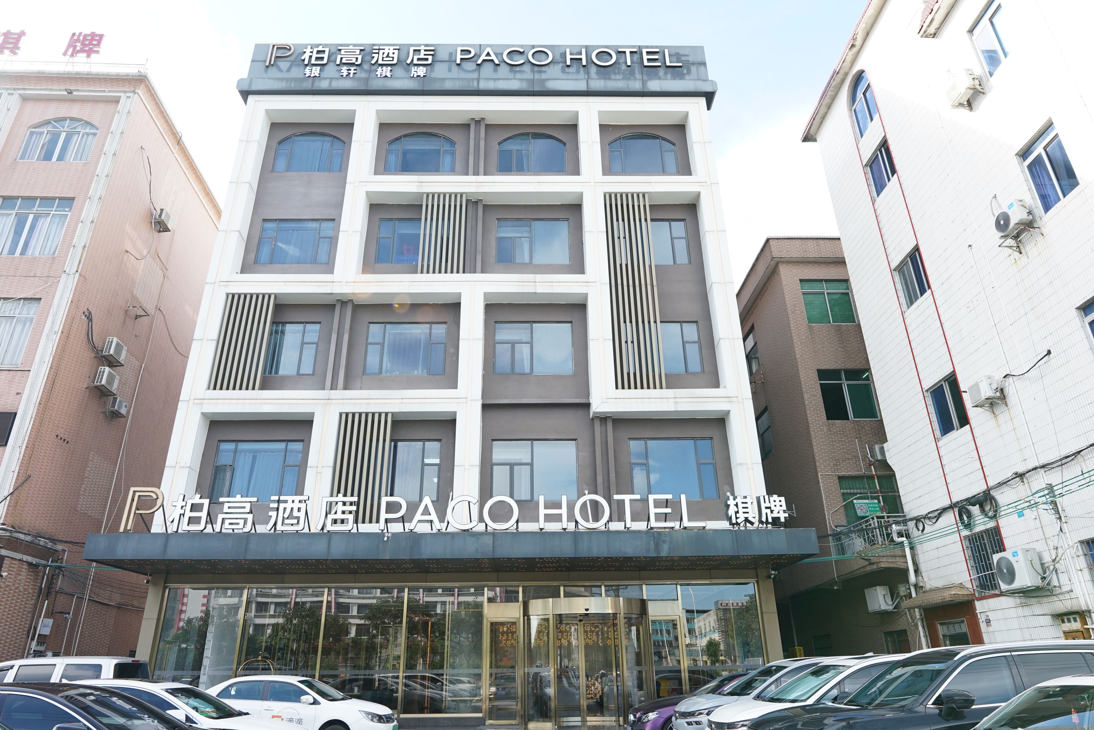 A multi-story hotel building with a prominent sign for Paco Hotel.