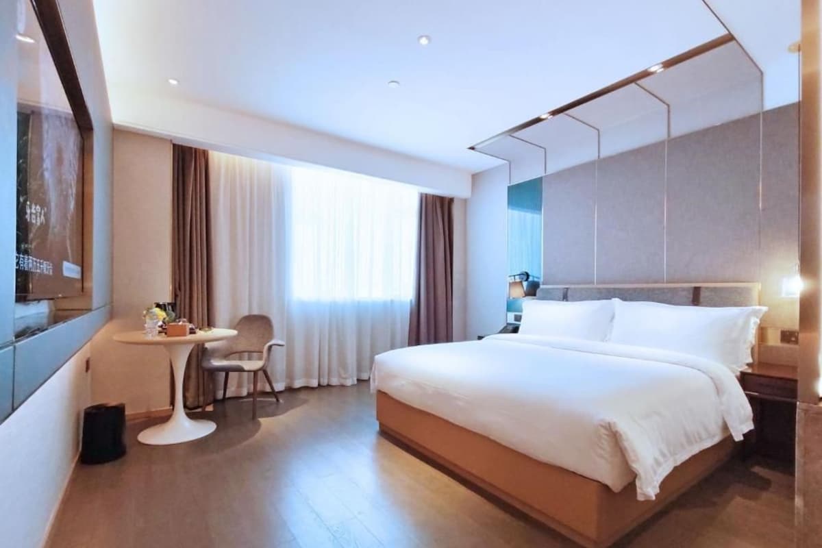 A modern hotel room with a large bed, a desk, and a chair.