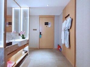 Un baño de hotel con un espejo grande, un lavamanos y un perchero para toallas.