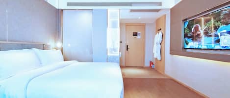 A hotel room with a large bed, a television mounted on the wall, and a robe hanging on the wall.
