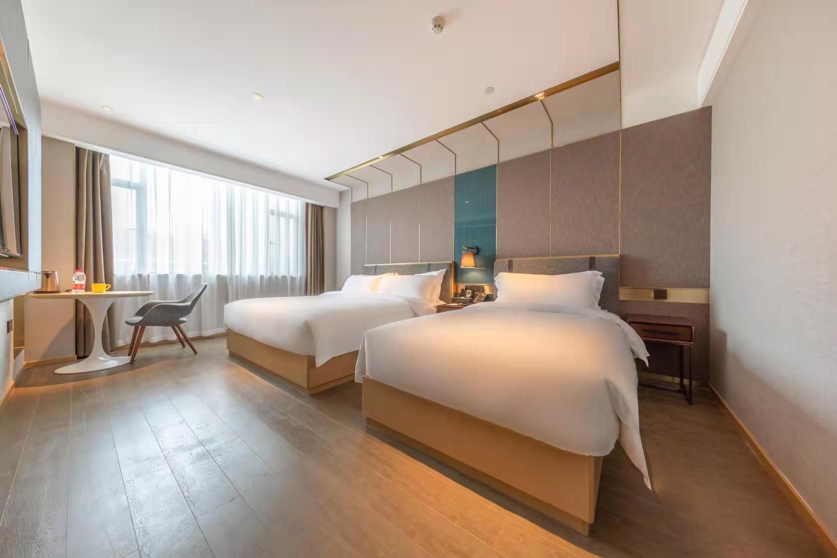 A hotel room with two beds, a desk, and a chair.
