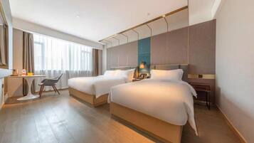 A hotel room with two beds, a desk, and a chair.