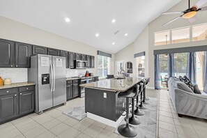 Una cocina moderna con una isla central, taburetes de bar y una zona de comedor con sofá.