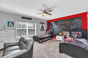 A bedroom with two beds, a ceiling fan, Star Wars themed decorations, and a Star Wars poster on the wall. - 6BD Mins to Disney | Pool, Spa, Theater, Game Room (Kissimmee)