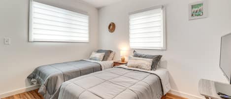 Un dormitorio con dos camas, un ventilador de techo y un escritorio con una silla.