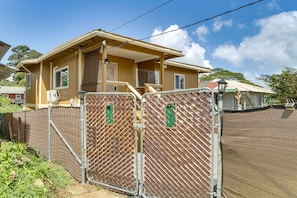 A two-story house with a fenced yard, a covered porch, and a satellite dish. - Modern Hilo Hideaway - Gated Yard Gazebo (Hilo)