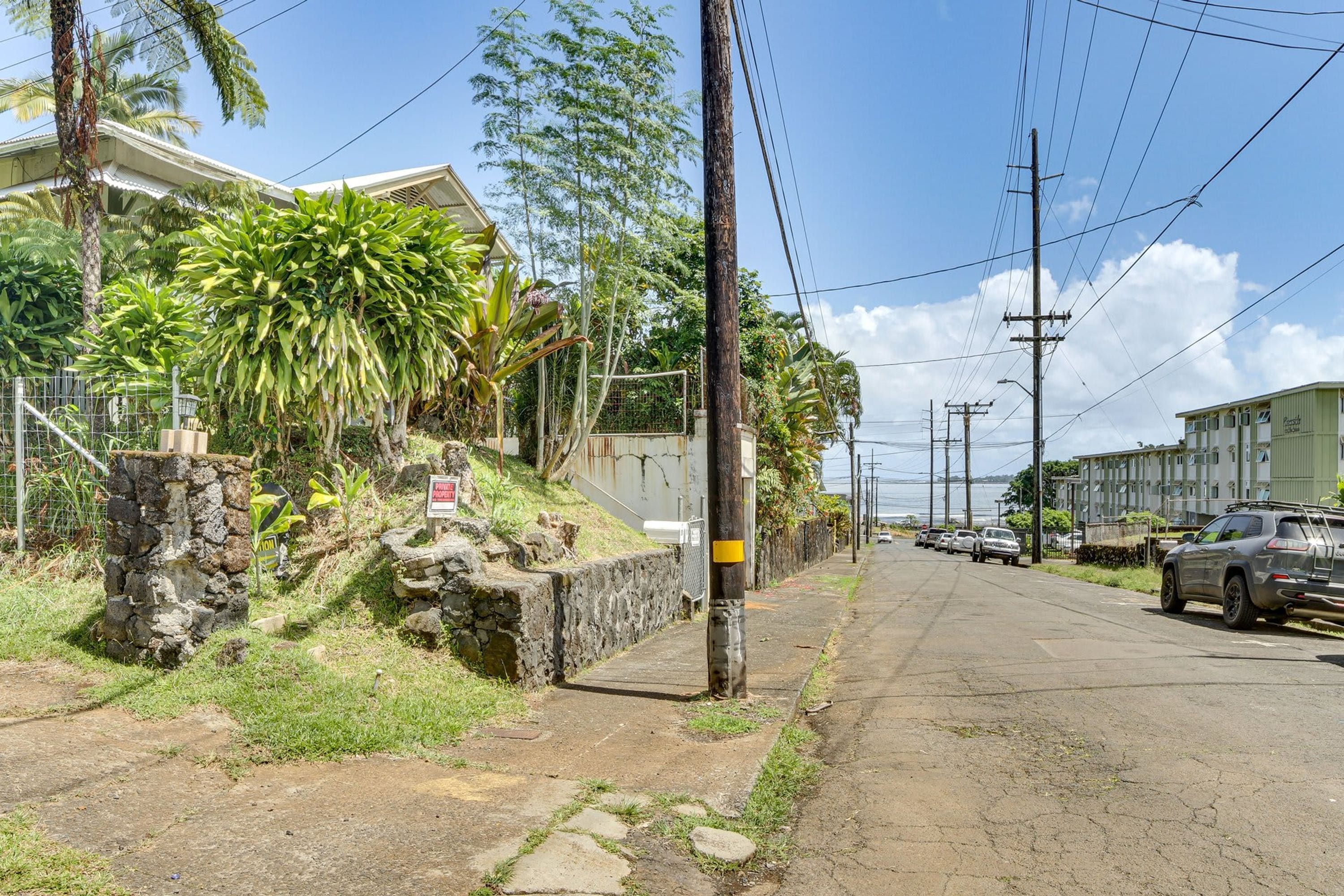 A street with a stone wall, a sign, and a parked car.