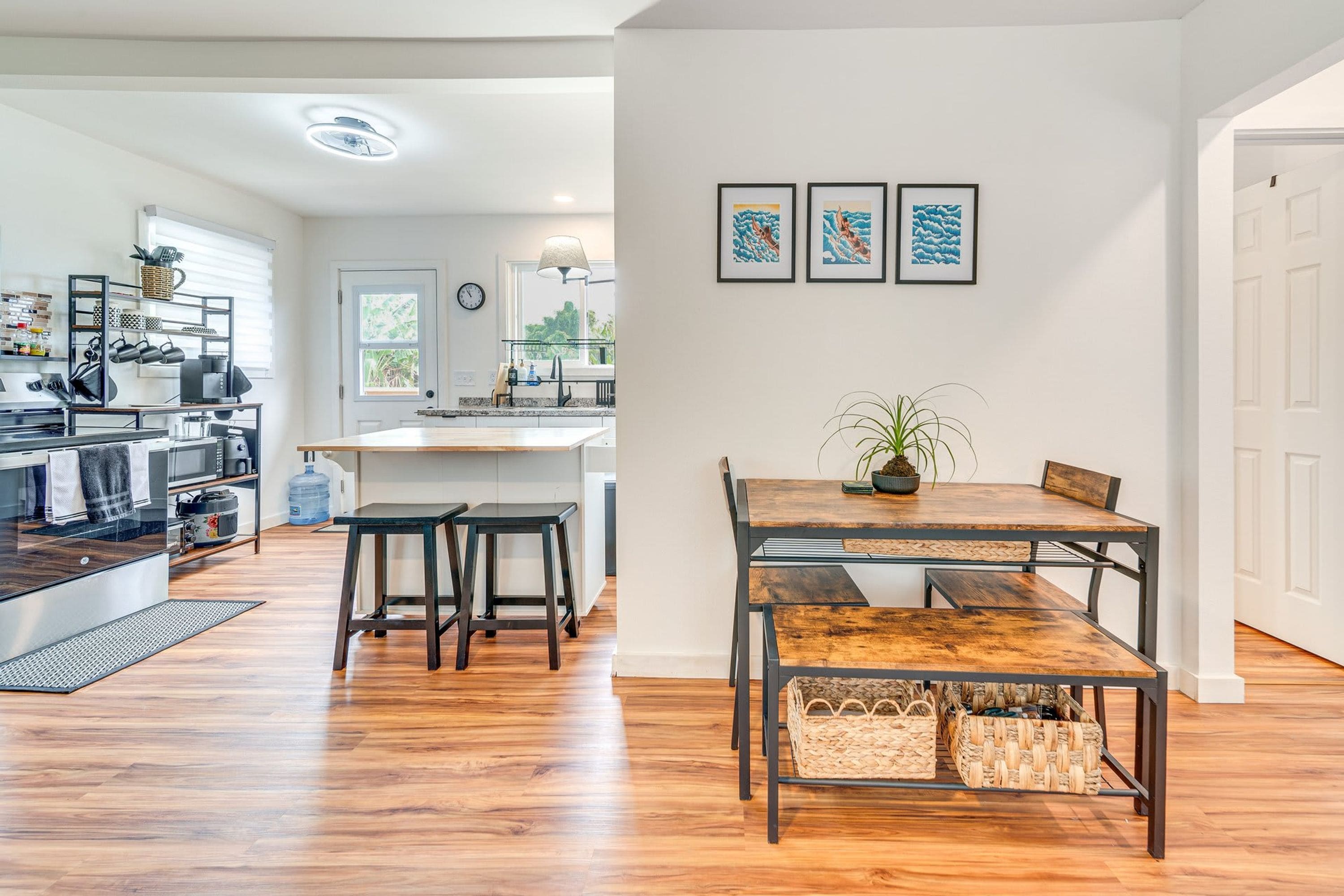 A modern kitchen with a central island, wooden flooring, and a dining area with a table and chairs.