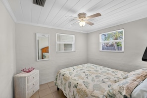 A bedroom with a bed, a ceiling fan, two windows with blinds, a dresser, and a mirror. - Lemon Bay Escape - Fishing 10 Min to Beach (Englewood)