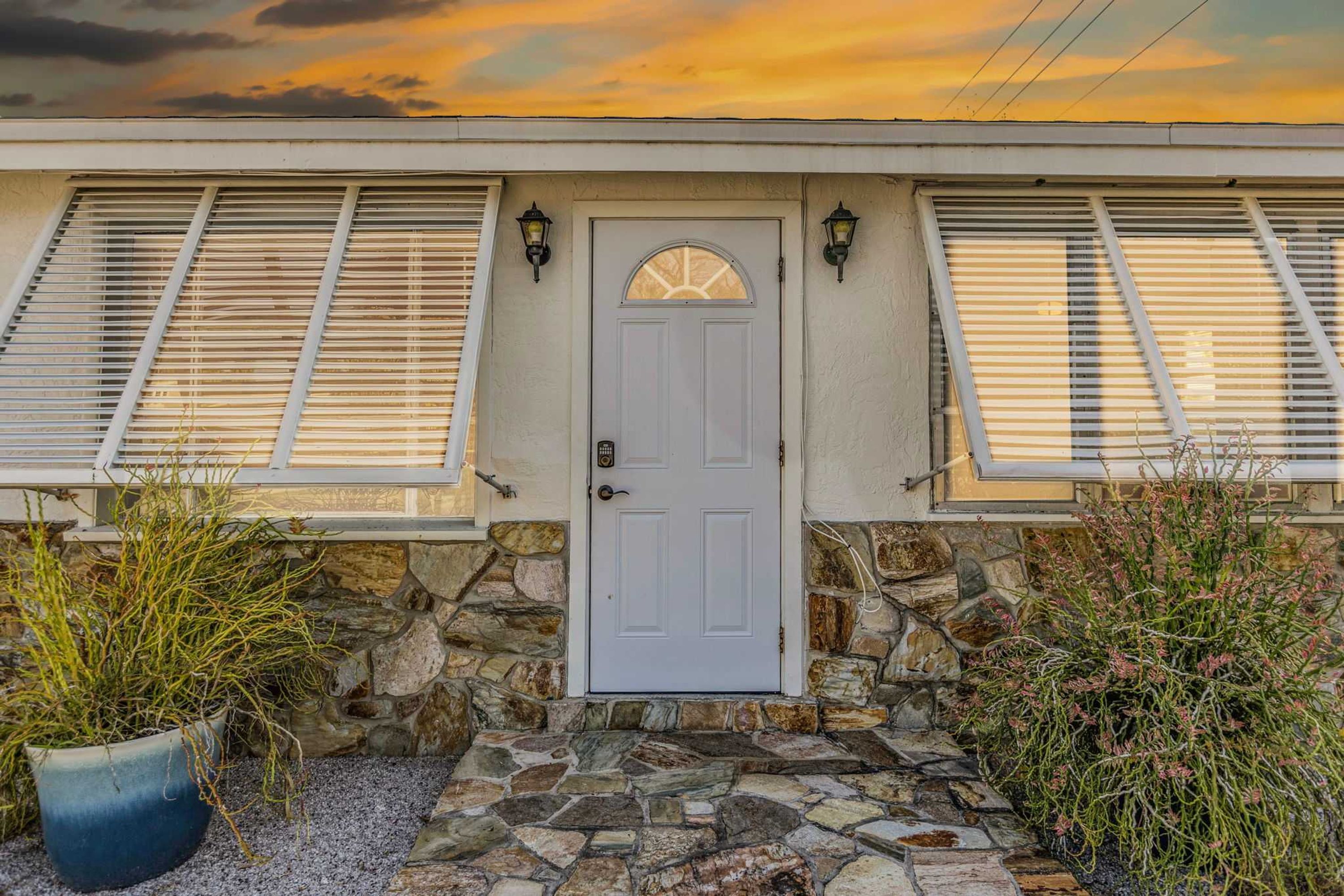 A house with a stone facade, a white door, and shutters on the windows.