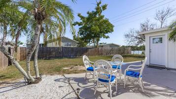 A patio with a table and chairs, a palm tree, and a wooden fence.