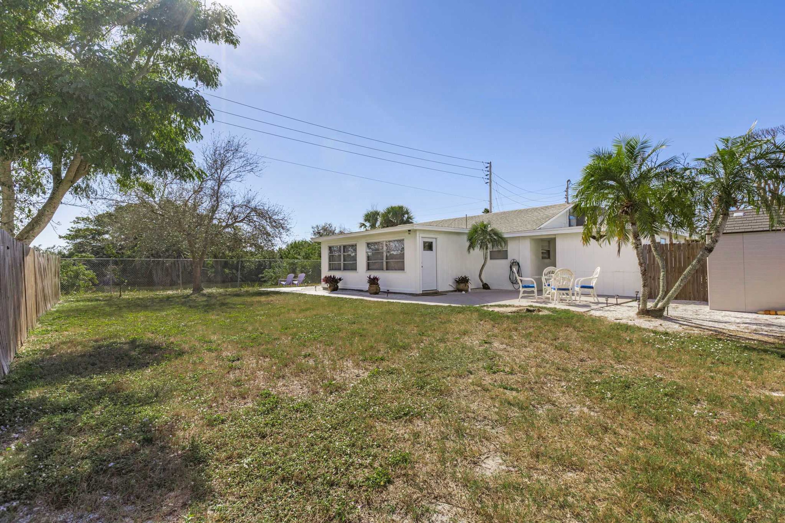 A single-story house with a front porch, a small attached garage, and a fenced backyard.