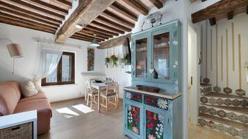 Una sala de estar acogedora con techo de madera, un comedor con mesa y sillas, y un aparador decorado con motivos florales.