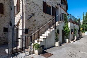 A stone building with a staircase, a metal gate, and potted plants.
