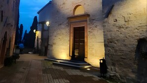 Una calle estrecha con un edificio que tiene una puerta de madera y un ventanal circular.