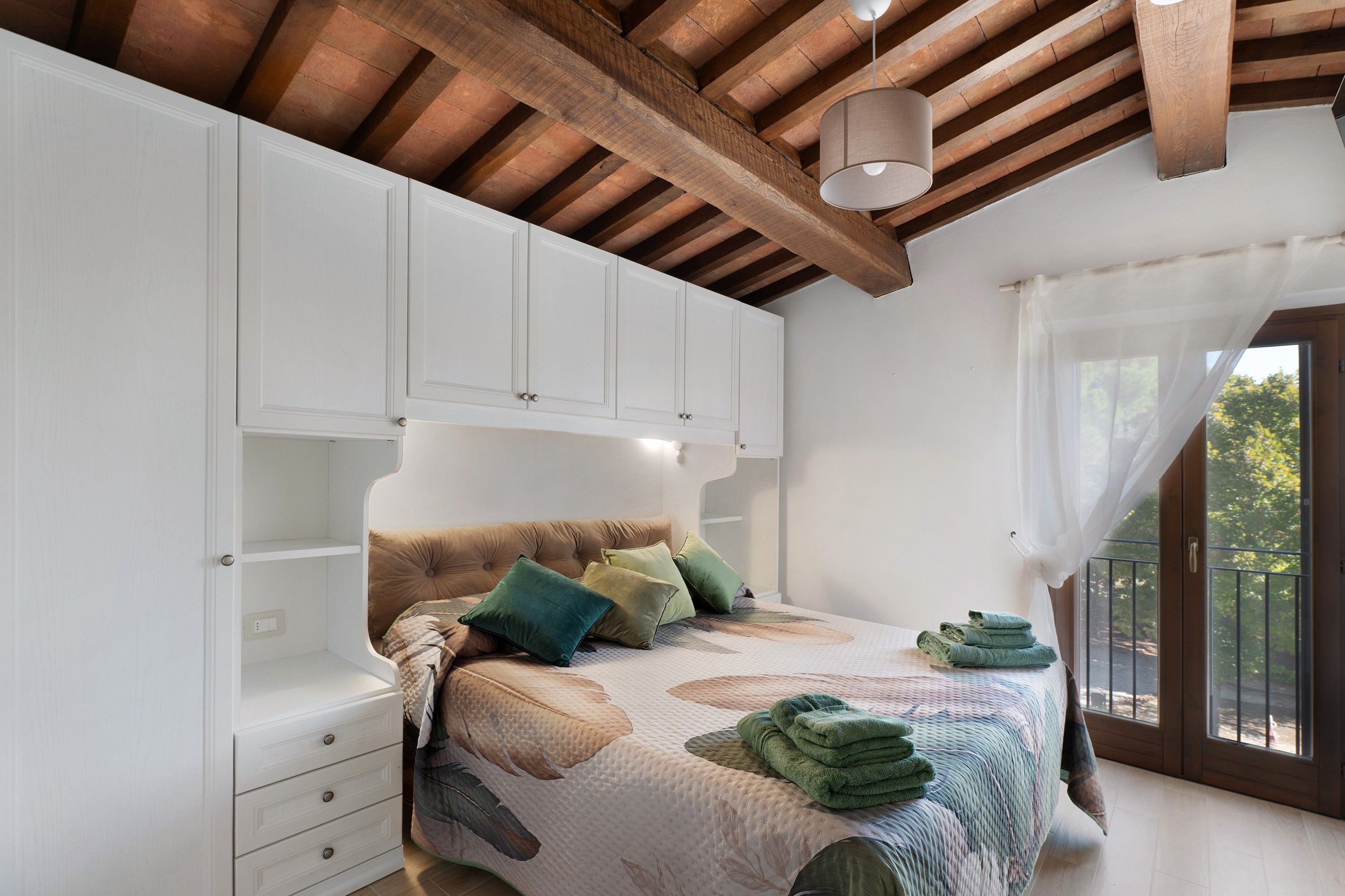 Ein Schlafzimmer mit Bett, Nachttisch, Kleiderschrank und einem Fenster mit Vorhängen.