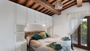 Ein Schlafzimmer mit Bett, Nachttisch, Kleiderschrank und einem Fenster mit Vorhängen.