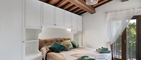 A bedroom with a bed, a nightstand, a wardrobe, and a window with curtains.