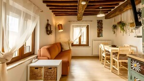 Un interior acogedor con techo de madera, un sofá, una mesa de comedor y un radiador.