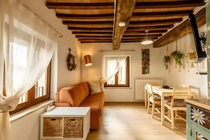 A cozy interior with a wooden ceiling, a sofa, a dining table, and a radiator.