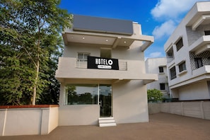 Um edifício moderno de hotel com uma placa que diz 'HOTELO' e 'OYO-SERVICED'.