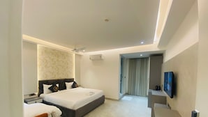 Habitación de hotel moderna con cama, zona de estar, televisión y baño visible a través de una puerta.