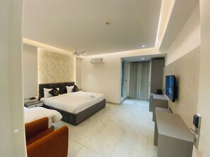 A modern hotel room with a bed, a seating area, a television, and a bathroom visible through a door. - Radhe Imperial (Hyderabad)
