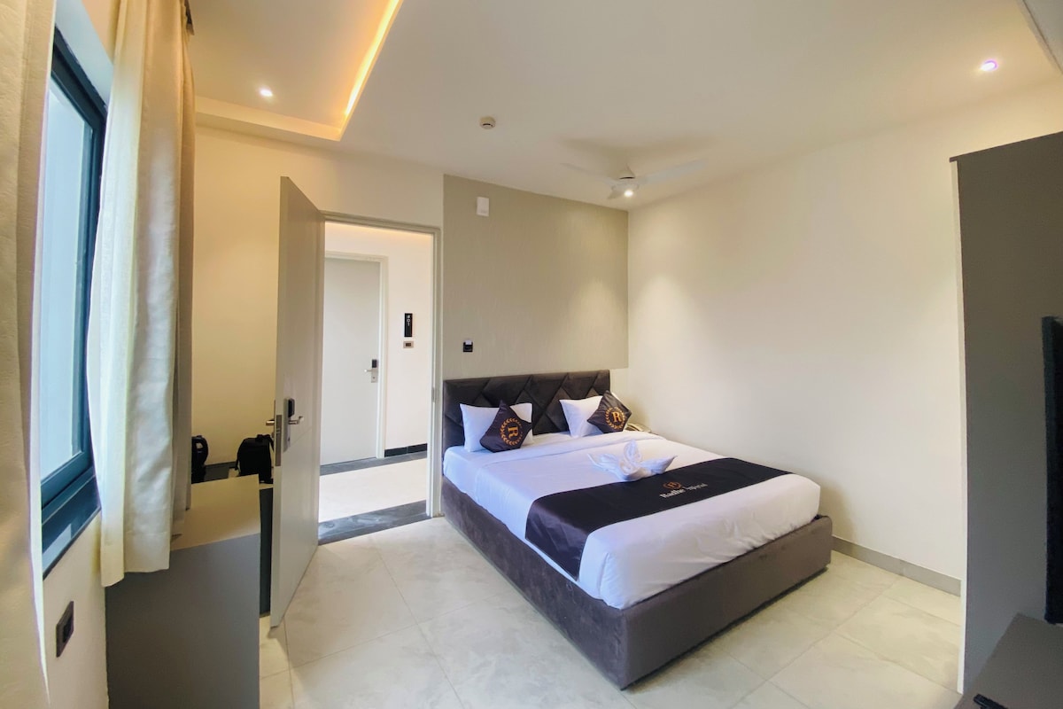 A hotel room with a bed, a door, and a view of the hallway.