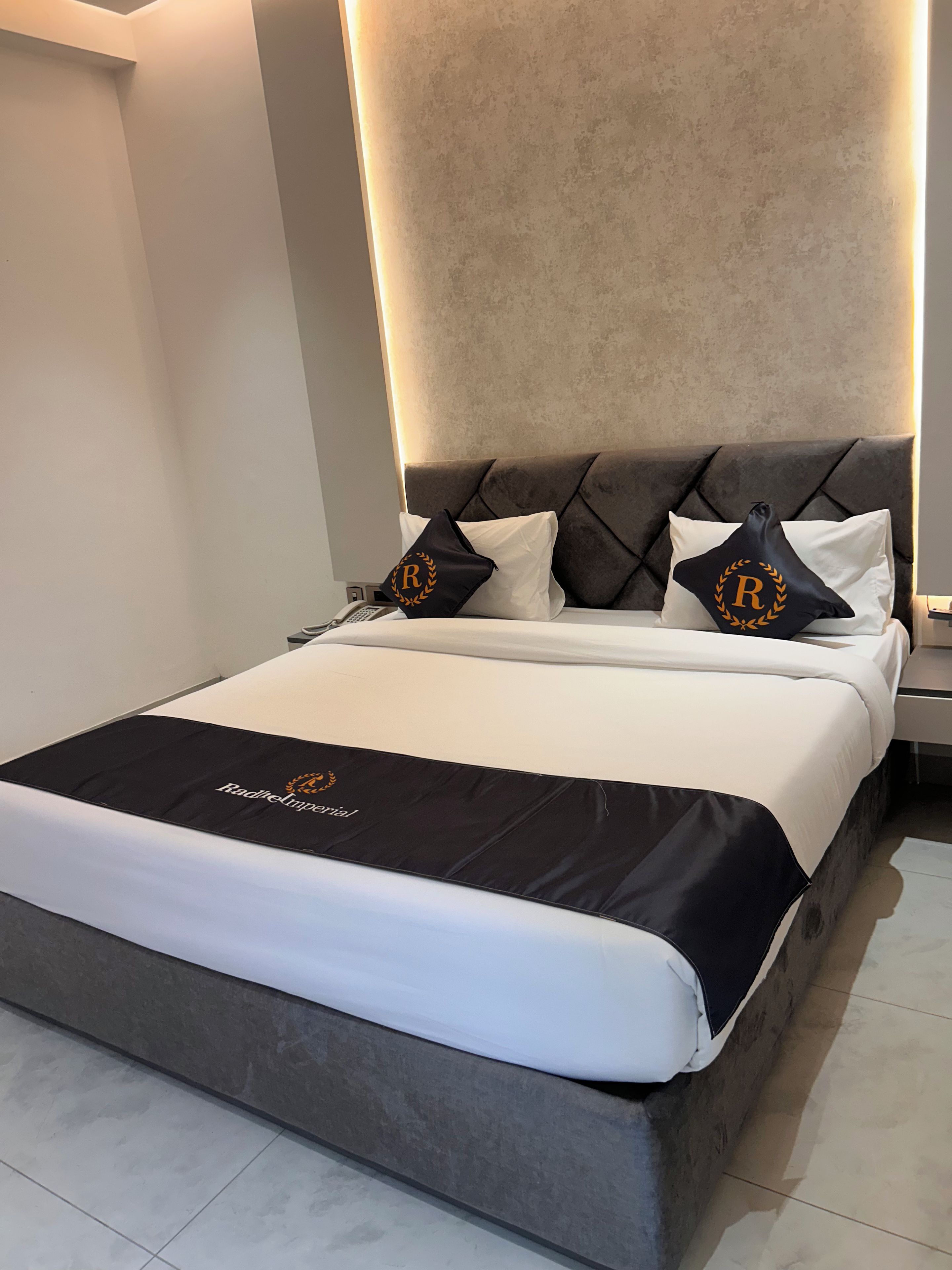 Une chambre d’hôtel avec un lit, une tête de lit et une table de chevet.