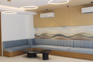 Zona d'espera moderna amb una disposició de seients corba, una taula de cafè i un aire condicionat fixat a la paret.