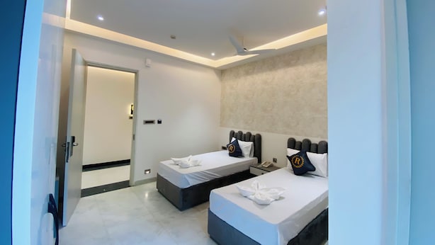 Una habitación de hotel moderna con dos camas, un baño y una puerta que da a otra habitación.