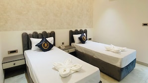 Habitación de hotel con dos camas, ventilador de techo, aire acondicionado y pared con textura.
