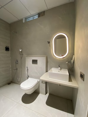 A modern bathroom with a toilet, sink, and shower. - Radhe Imperial (Hyderabad)