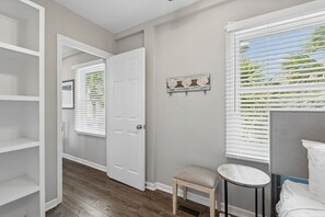 A hallway with a white door, a small stool, and a bed with white bedding. - Atlantic High- 1 Summer Dunes-  Sleeps 22, PeekaBoo Views & Elevator! (Isle of Palms)