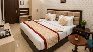 Una habitación de hotel con cama, mesita de noche, una pequeña mesa redonda, un armario y una puerta.