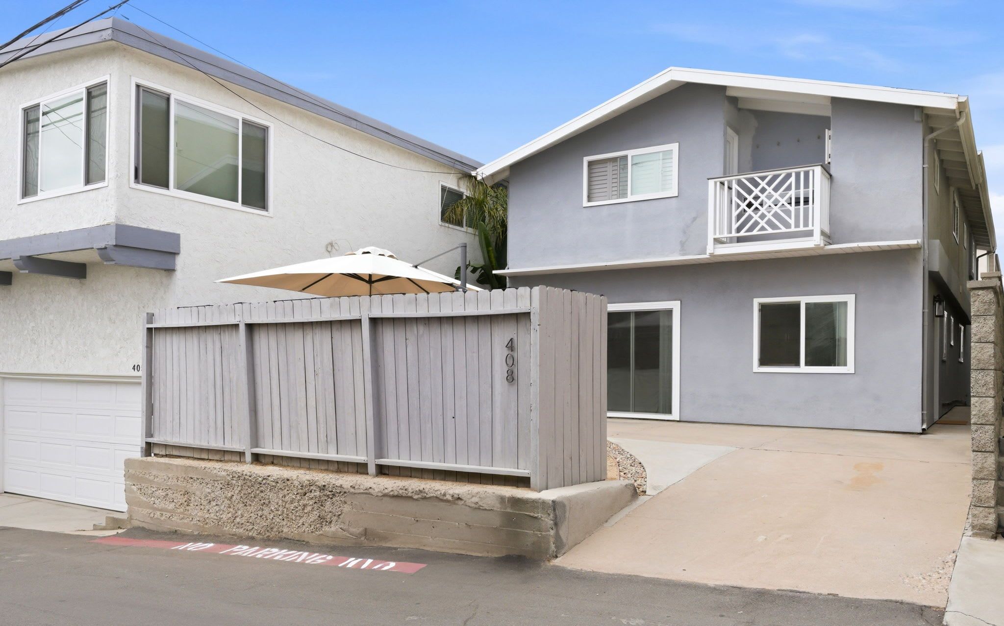A two-story residential building with a garage, a balcony, and a fenced area with a number 408.