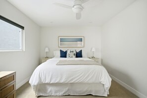 A bedroom with a bed, bedside tables, a ceiling fan, a window, and a framed picture on the wall. - Coastal Manhattan Beach Home | Walk to Beach & Downtown (Manhattan Beach)