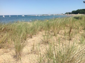 A beach with tall grass in the foreground and a clear view of the sea with boats in the distance. - Strandhaus Clara: Large Terrace & Sea View at Timmendorfer Strand (Timmendorfer Strand)