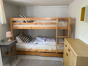 A bunk bed with a desk and a dresser, a lamp, and a striped rug. - Strandhaus Clara: Large Terrace & Sea View at Timmendorfer Strand (Timmendorfer Strand)
