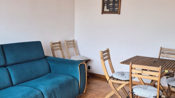 A living room with a blue sofa, wooden chairs, a wooden table, and a herringbone-patterned wooden floor. - Due Passi di Blu: Your own little oasis of relaxation just a few steps from the sea in Anzio (Anzio)