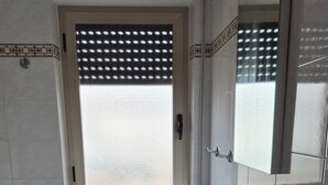 Ett badrum med ett fönster, ett handfat, en toalett och ett element.