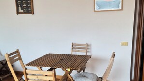 En matplats med ett träbord och stolar, en inramad tavla på väggen och en liten skylt med symboler.