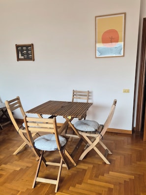 A dining area with a wooden table and chairs, a framed picture on the wall, and a small sign with symbols. - Due Passi di Blu: Your own little oasis of relaxation just a few steps from the sea in Anzio (Anzio)