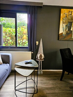 A living room with a sofa, a small table, a lamp, and a painting on the wall. - The Veluwe Nest (Epe)