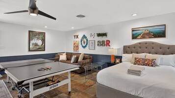 A hotel room with a bed, a table tennis table, a sofa, and a ceiling fan.