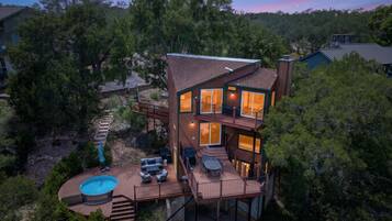 A multi-level wooden house with a deck, outdoor seating, and a swimming pool.