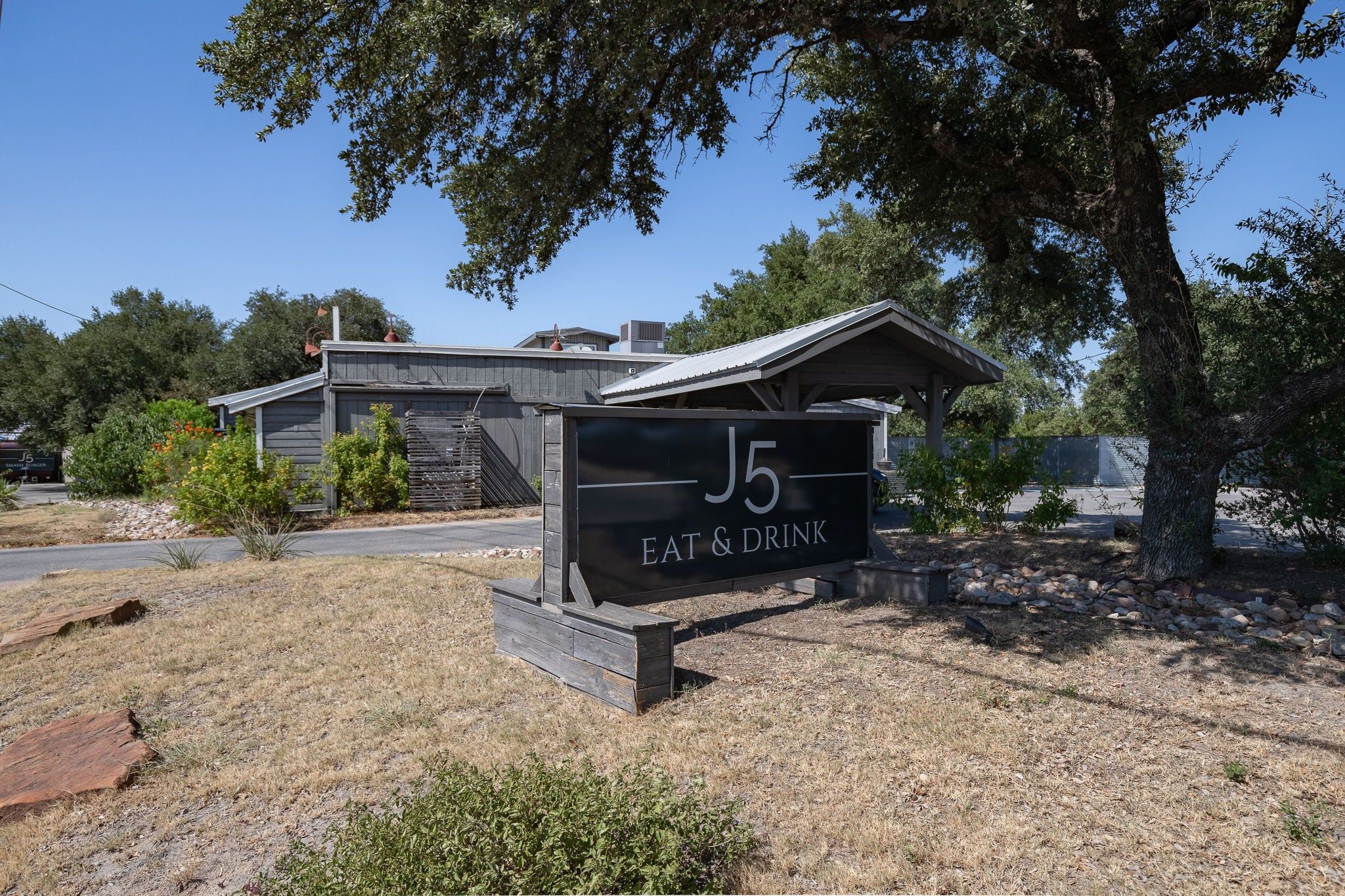 A sign for 'J5 Eat & Drink' with a building in the background.
